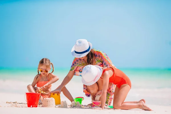 Matka i małe córeczki robiące zamek z piasku na tropikalnej plaży — Zdjęcie stockowe