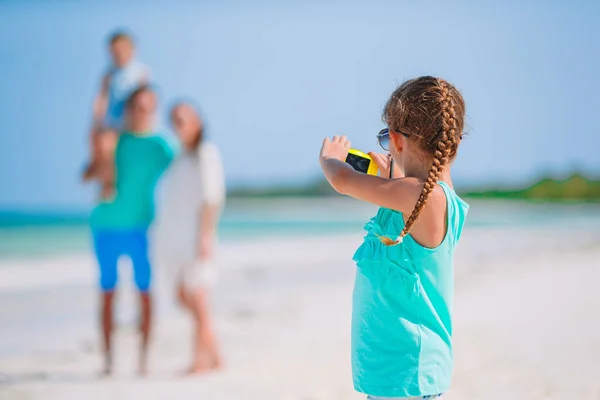 Little girl making photo on phone of family at the beach — Stock Photo, Image