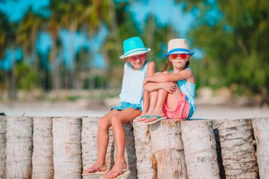 Küçük mutlu komik kızlar tropikal plajda birlikte oynarken çok eğlenirler..