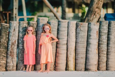 Küçük mutlu komik kızlar tropikal plajda birlikte oynarken çok eğlenirler..