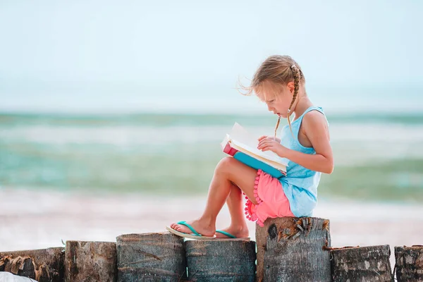 Little adorable girl reading book during tropical white beach — Stock Photo, Image