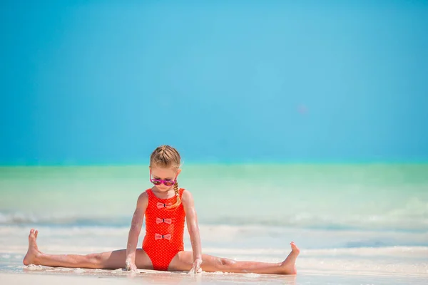 Aktives kleines Mädchen am weißen Strand, das Spaß hat — Stockfoto