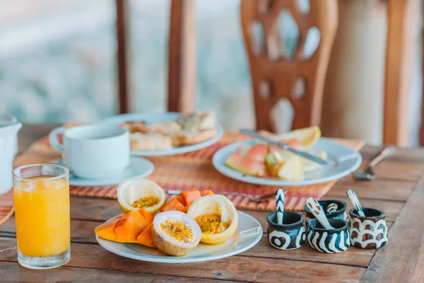 Sabrosas frutas exóticas - fruta de la pasión madura, mango en el desayuno en restaraunt al aire libre —  Fotos de Stock