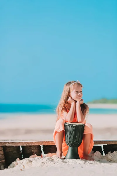 Klein gelukkig meisje spelen op afrikaanse drums. — Stockfoto