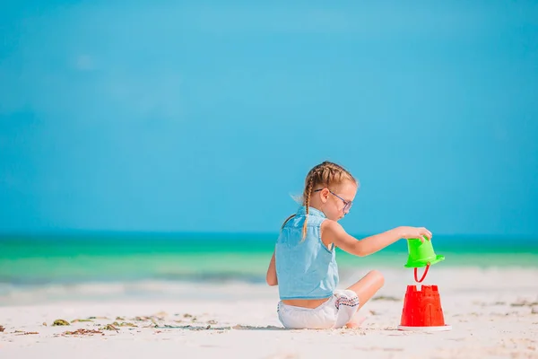 Adorabile bambina che gioca con i giocattoli della spiaggia sulla spiaggia tropiale bianca — Foto Stock