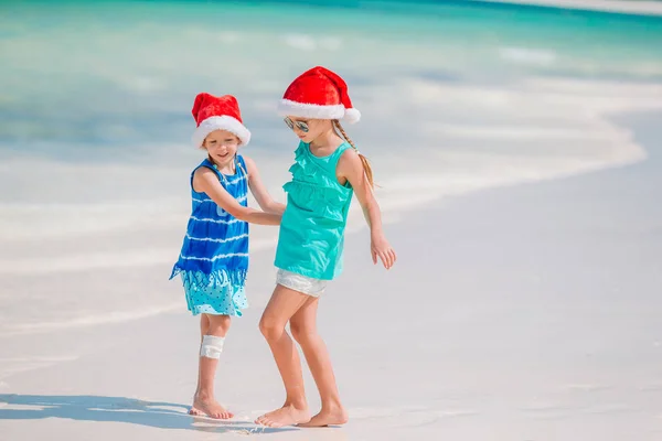 Urocze, małe dzieci w Santa hat w Boże Narodzenie wakacje na plaży. Nowy rok na plaży — Zdjęcie stockowe