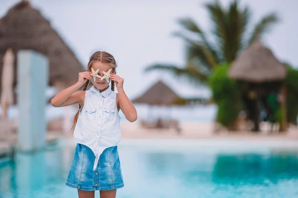 Очаровательная маленькая девочка с морской звездой на белом пустом пляже — стоковое фото
