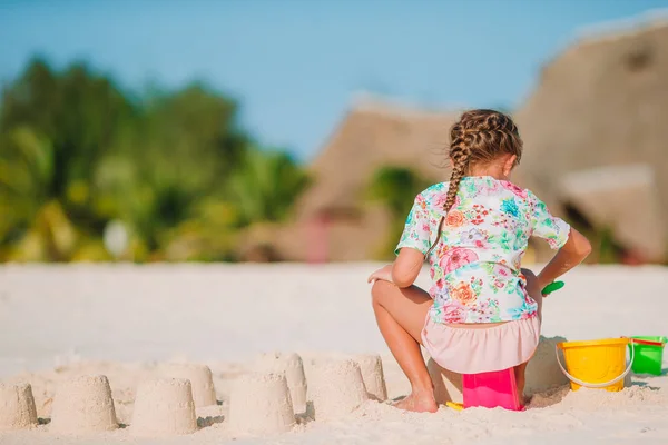 Klein meisje op tropisch wit strand maken zand kasteel — Stockfoto