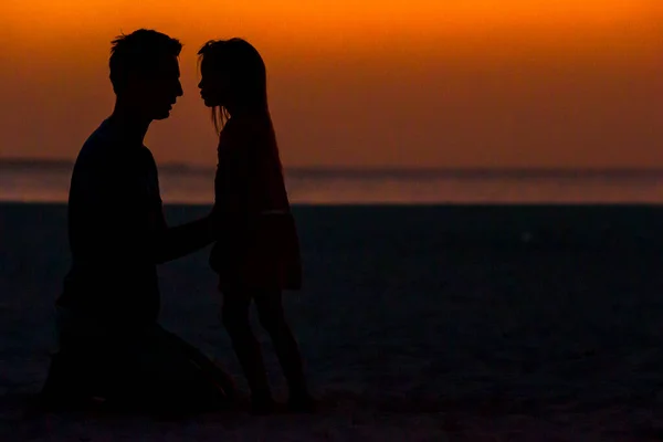 Little girl and dad silhouette in the sunset at the beach — Stock Photo, Image