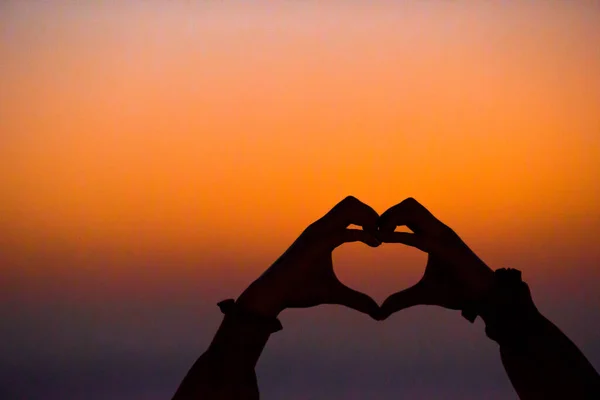 Sylwetka serca wykonane przez dzieci rękę na zachodzie słońca — Zdjęcie stockowe