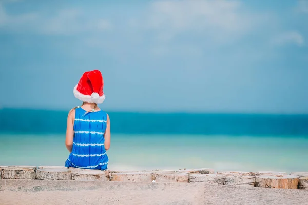 Adorable little girl in Santa hat on tropical beach — Stock Photo, Image