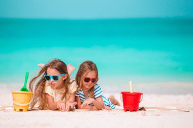 İki küçük mutlu kız tropikal plajda birlikte oynarken çok eğleniyor.