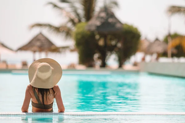 Mujer relajándose junto a la piscina en un complejo hotelero de lujo disfrutando de vacaciones perfectas en la playa — Foto de Stock