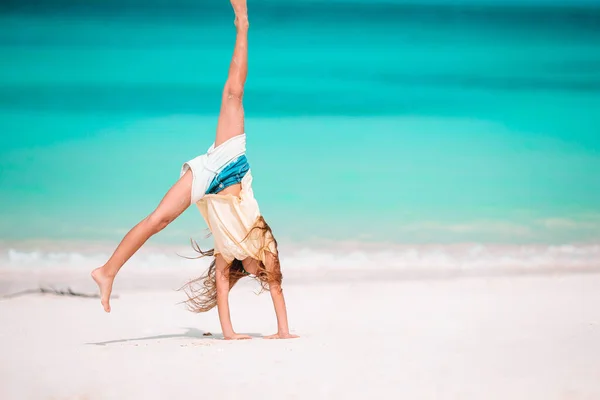 Активная маленькая девочка на пляже, развлекающаяся на берегу, совершает прыжок — стоковое фото