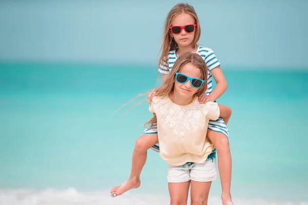 Pequeñas chicas divertidas felices tienen un montón de diversión en la playa tropical jugando juntos. Día soleado con lluvia en el mar —  Fotos de Stock