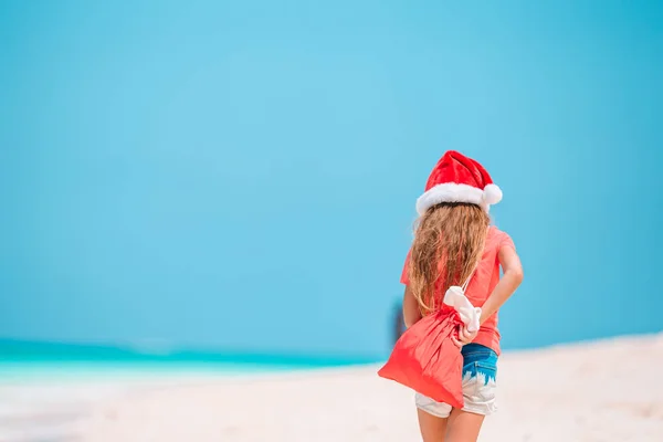 Entzückendes kleines Mädchen mit Weihnachtsmütze am tropischen Strand — Stockfoto
