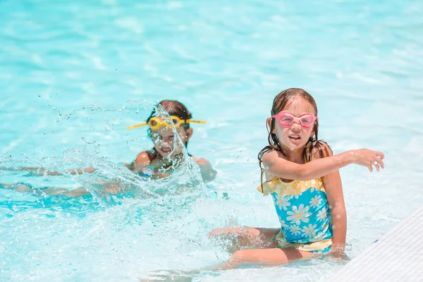 Очаровательные маленькие девочки играют в открытом бассейне на отдыхе — стоковое фото