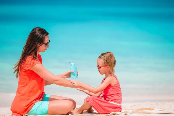 Junge Mutter cremt Tochter am Strand mit Sonnencreme ein Sonnenschutz — Stockfoto