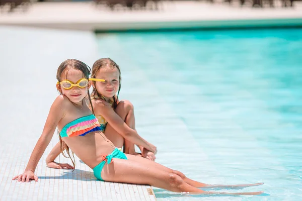 Очаровательные маленькие девочки играют в открытом бассейне на отдыхе — стоковое фото