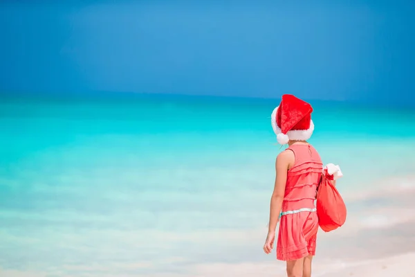 Schattig meisje in Kerstman hoed op tropisch strand — Stockfoto