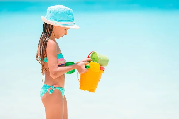 Nuttet lille pige leger med strand legetøj på hvid tropial strand - Stock-foto