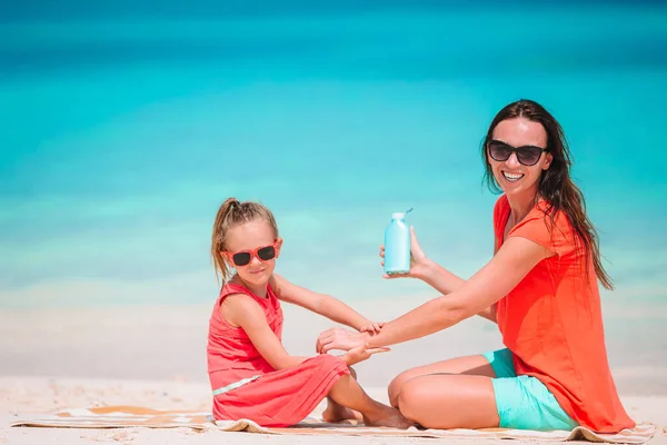 Young mother applying sun cream to daughter nose on the beach. Sun protection — Stock Photo, Image