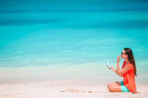 Mooie jonge vrouw met een zonnebrandcrème liggend op tropisch strand — Stockfoto