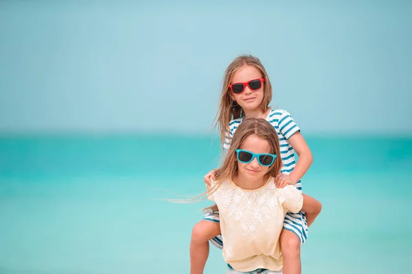 Kleine fröhliche lustige Mädchen haben viel Spaß am tropischen Strand, wo sie zusammen spielen. Sonniger Tag mit Regen im Meer — Stockfoto