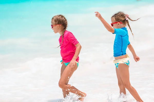 Pequeñas chicas divertidas felices tienen un montón de diversión en la playa tropical jugando juntos. Día soleado con lluvia en el mar —  Fotos de Stock