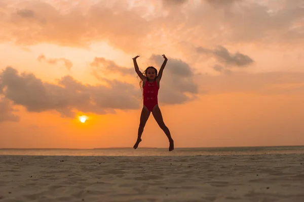 Adorável menina feliz na praia branca ao pôr do sol. — Fotografia de Stock