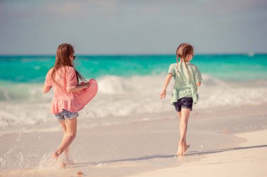 Küçük mutlu komik kızlar tropikal plajda birlikte oynarken çok eğlenirler..