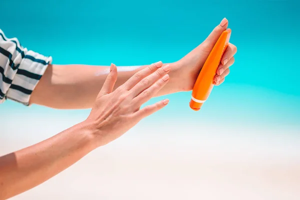 Hermosa joven sosteniendo una crema solar acostada en la playa tropical — Foto de Stock