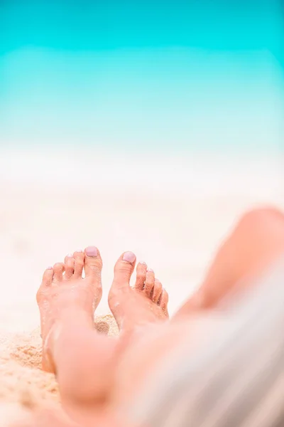 Womans voeten op het witte zandstrand in ondiep water — Stockfoto