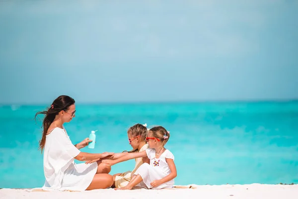 Madre joven aplicando crema solar a la nariz de la hija en la playa. Protección solar —  Fotos de Stock