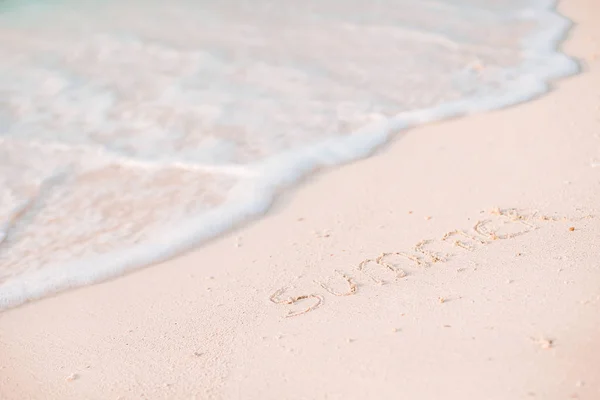 Palabra de verano escrito a mano en la playa de arena con ola suave del océano en el fondo —  Fotos de Stock