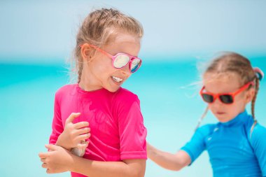 Küçük mutlu komik kızlar tropikal plajda birlikte oynarken çok eğlenirler..