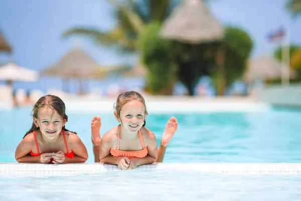 Adorable little girls playing in outdoor swimming pool on vacation — Stock Photo, Image