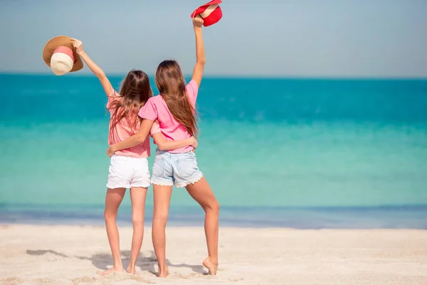 Küçük mutlu komik kızlar tropikal plajda birlikte oynarken çok eğleniyorlar. Denizde yağmurlu güneşli bir gün — Stok fotoğraf