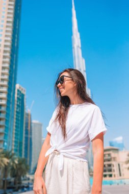 Arka planda Burj Halife gökdeleniyle Dubai 'de yürüyen mutlu kadın..