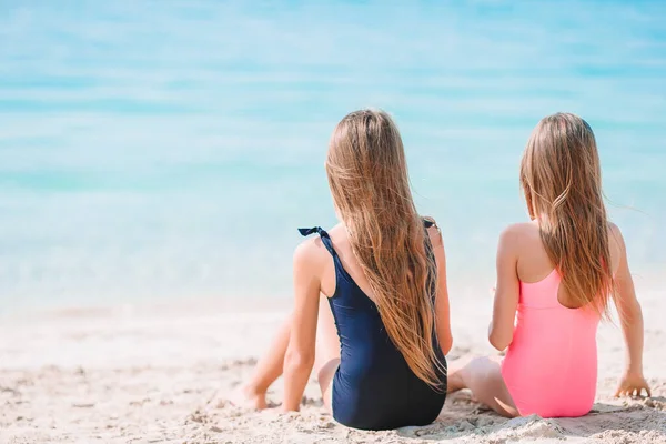 Małe szczęśliwe śmieszne dziewczyny mają dużo zabawy na tropikalnej plaży bawiąc się razem. Słoneczny dzień z deszczem w morzu — Zdjęcie stockowe