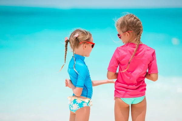 Pequeñas chicas divertidas felices tienen un montón de diversión en la playa tropical jugando juntos. Día soleado con lluvia en el mar — Foto de Stock