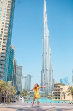 Happy girl walking in Dubai with Burj Khalifa skyscraper in the background.