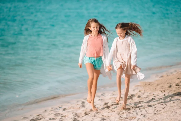 Kleine fröhliche lustige Mädchen haben viel Spaß am tropischen Strand, wo sie zusammen spielen. Sonniger Tag mit Regen im Meer — Stockfoto