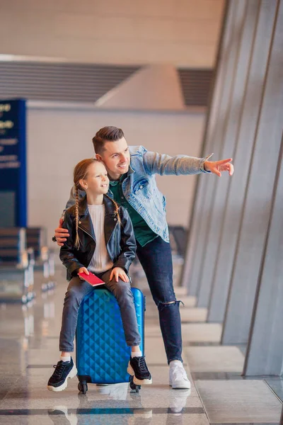 Familia feliz con equipaje y tarjeta de embarque en el aeropuerto esperando el embarque —  Fotos de Stock