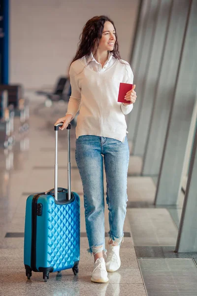 Mujer joven con equipaje en el aeropuerto internacional. Pasajero de aerolínea en un salón del aeropuerto esperando aviones de vuelo —  Fotos de Stock