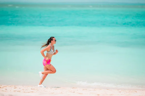 Jonge vrouw op het tropische strand in sportkleding passen — Stockfoto