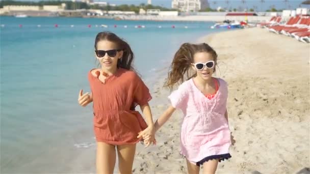 Little happy funny girls have a lot of fun at tropical beach playing together. Sunny day with rain in the sea — Stock Video