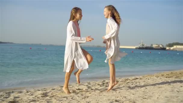 Piccole ragazze divertenti felici si divertono molto alla spiaggia tropicale a giocare insieme. Giorno soleggiato con pioggia nel mare — Video Stock
