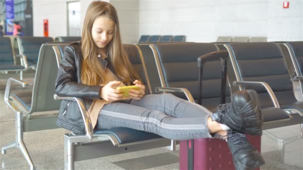 Schattig klein meisje op de luchthaven in grote internationale luchthaven in de buurt van venster — Stockvideo