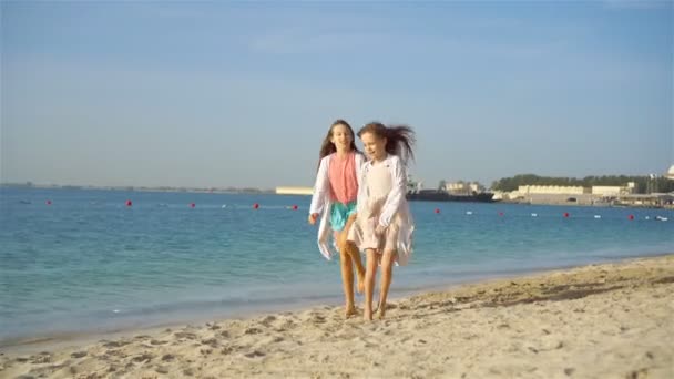 Pequenas meninas engraçadas felizes se divertir muito na praia tropical jogando juntos. Dia ensolarado com chuva no mar — Vídeo de Stock